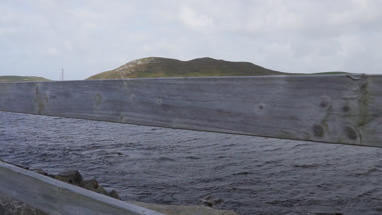 Slow motion reveal shot of boats harbored on a windy day in the Atlantic Ocean and an island in the background in Ireland in 4K