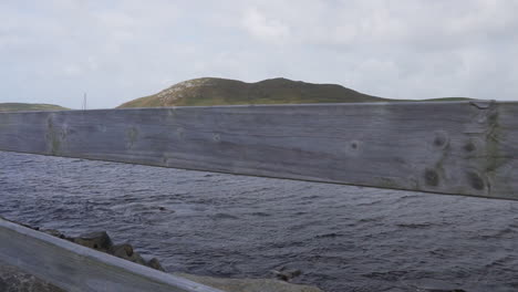 Slow-motion-reveal-shot-of-boats-harbored-on-a-windy-day-in-the-Atlantic-Ocean-and-an-island-in-the-background-in-Ireland-in-4K