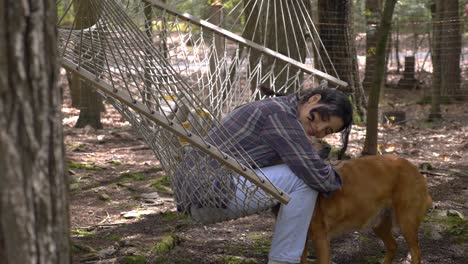 happy puerto rican girl swinging in woodland hammock hugging dog companion