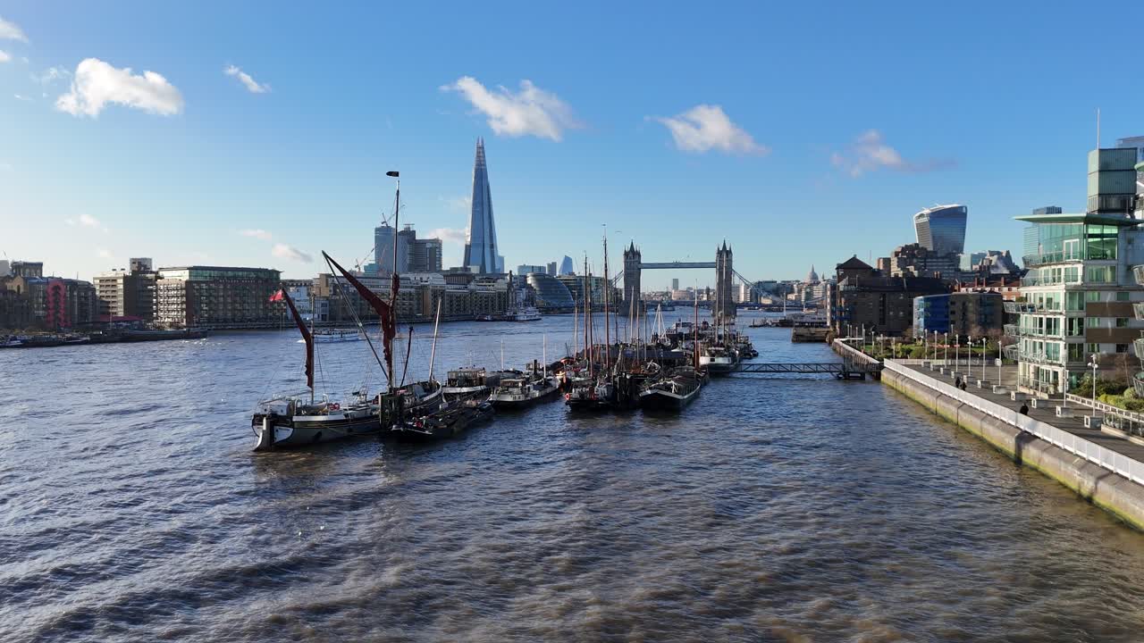 Ascending drone,aerial Old sailing barges moored on river Thames Tower bridge London UK in background