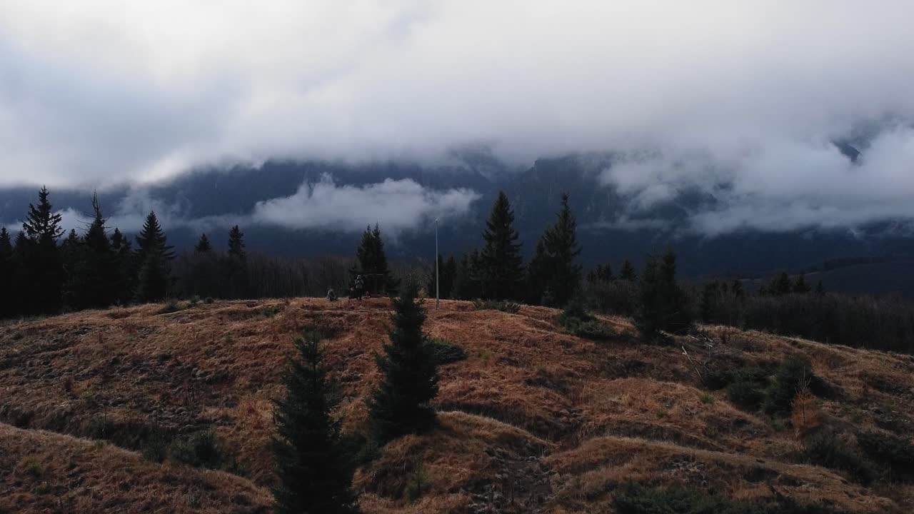 drone volando hacia arriba revelando un pico de montaña con pinos y niebla en el fondo