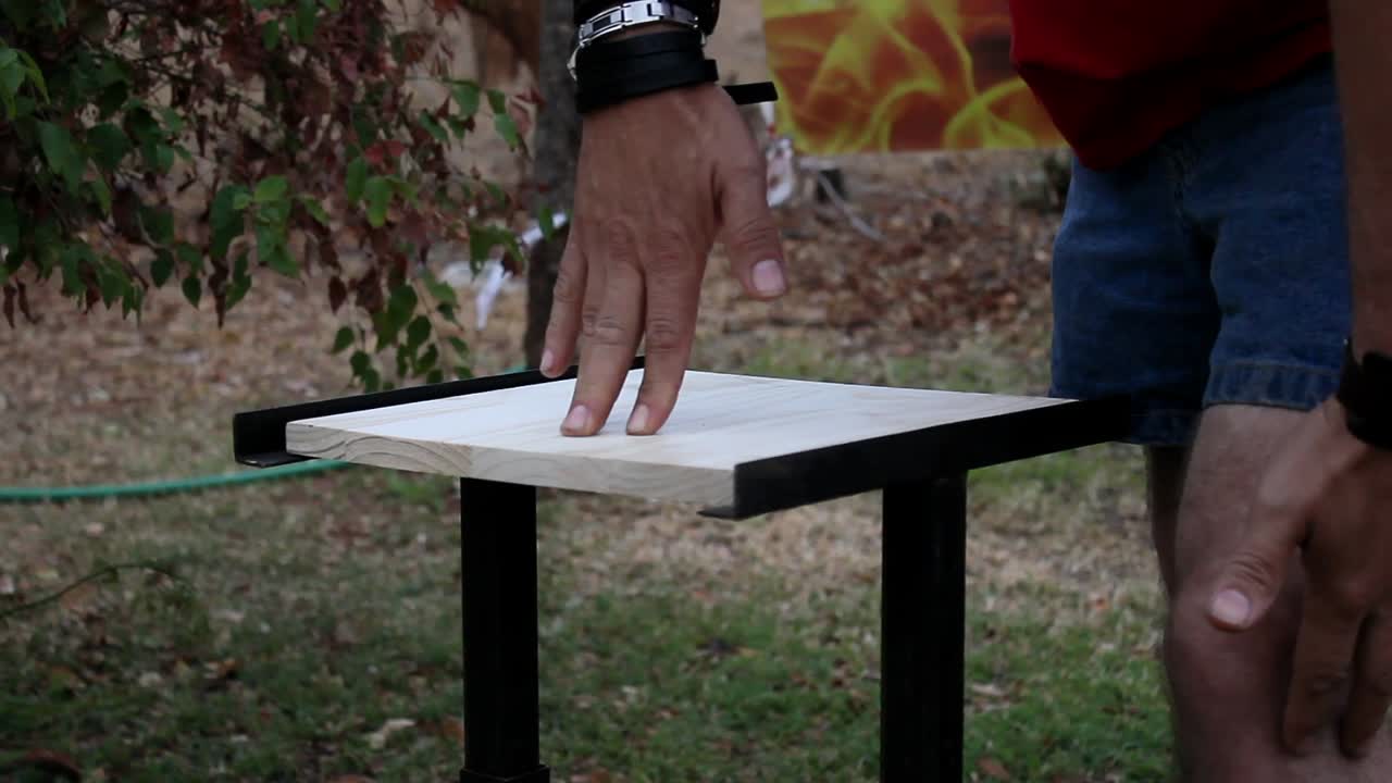 Man preparing to break wooden board without lifting his fingers from the board. The wooden board breaks in two