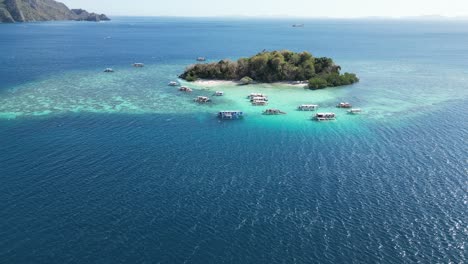 tomada larga del dron de la isla cyc en coron con barcos de excursión en el arrecife en un día soleado