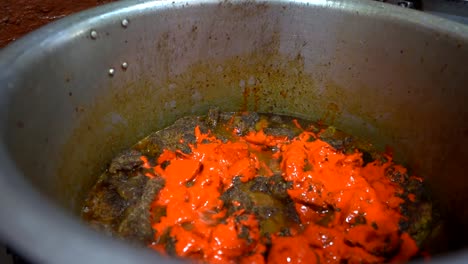 cooking and garnishing bubbling indian chicken curry with chilies and spices