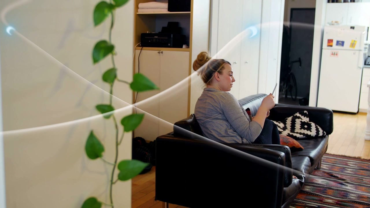 Woman sitting sofa raising phone, checking social messages while light streaks passing frame