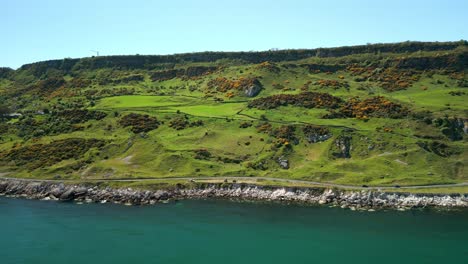 ultra-wide, advancing aerial video of the causeway coastal route at glenarm in county antrim, northern ireland, uk on a bright and sunny day. filmed in 4k, 60fps and with rec709 color.