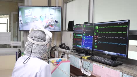médico monitoreando al paciente infectado con covid-19 a través de la pantalla de la unidad de aislamiento