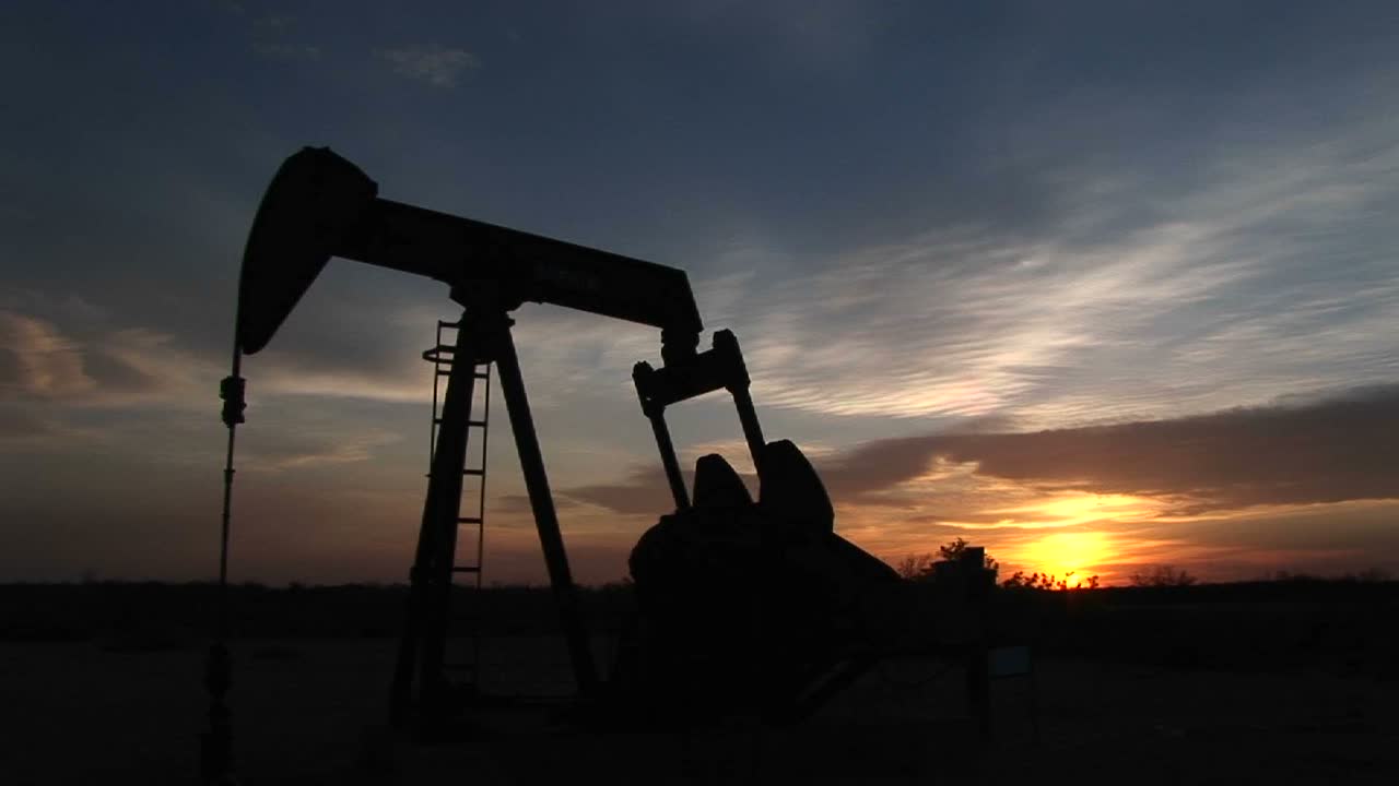 plano medio de una bomba de aceite silueteada girando en el desierto de nuevo méxico bombeando petróleo