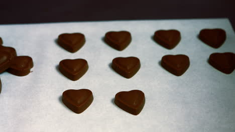 worker arranging heart shaped dark chocolate on tray