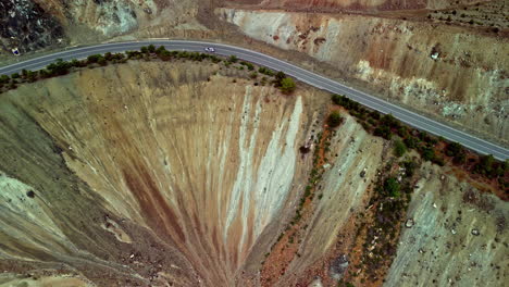 disparo de panorámica aérea de un avión no tripulado siguiendo a un coche que conduce por una carretera de montaña