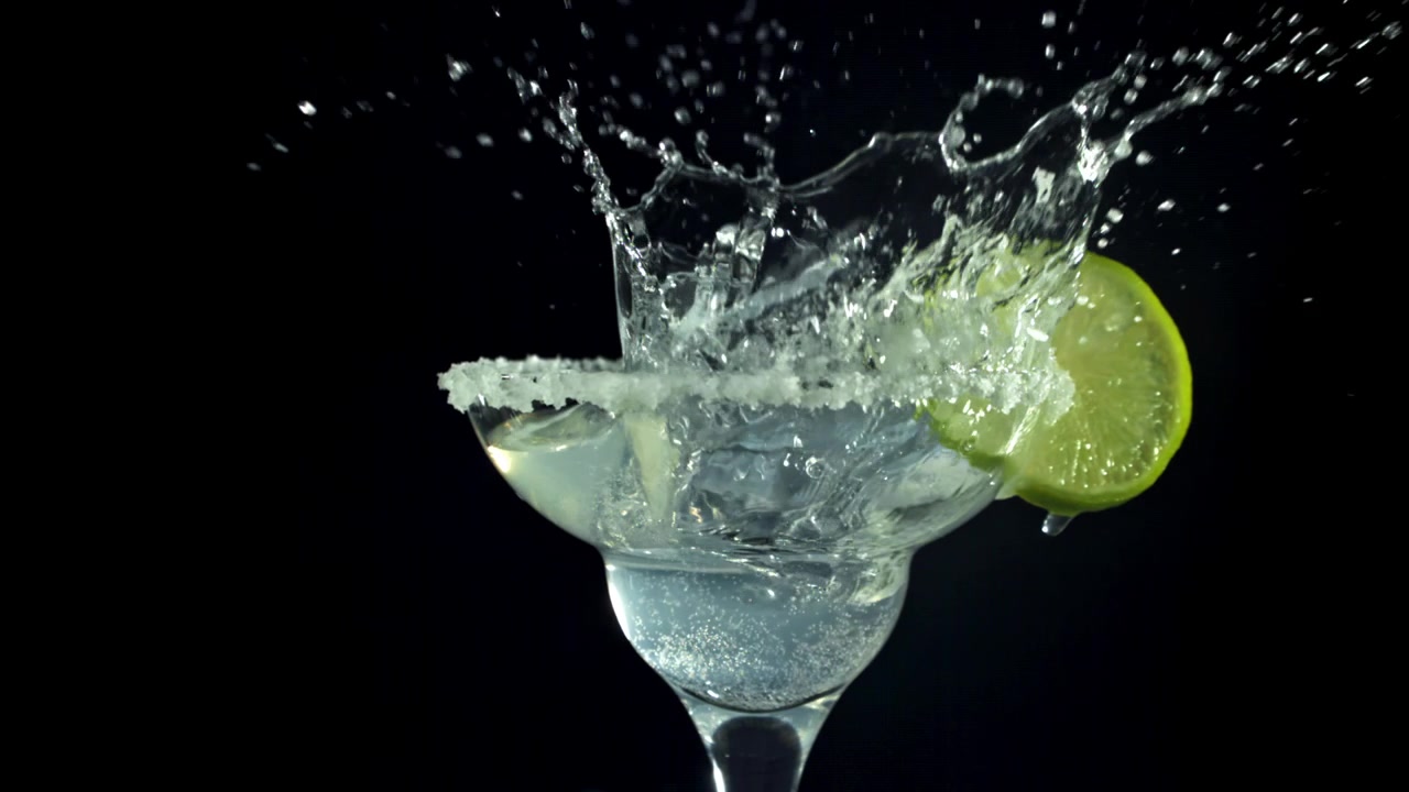 Cubetto di ghiaccio che schizza in un Margarita con bordo salato e lime