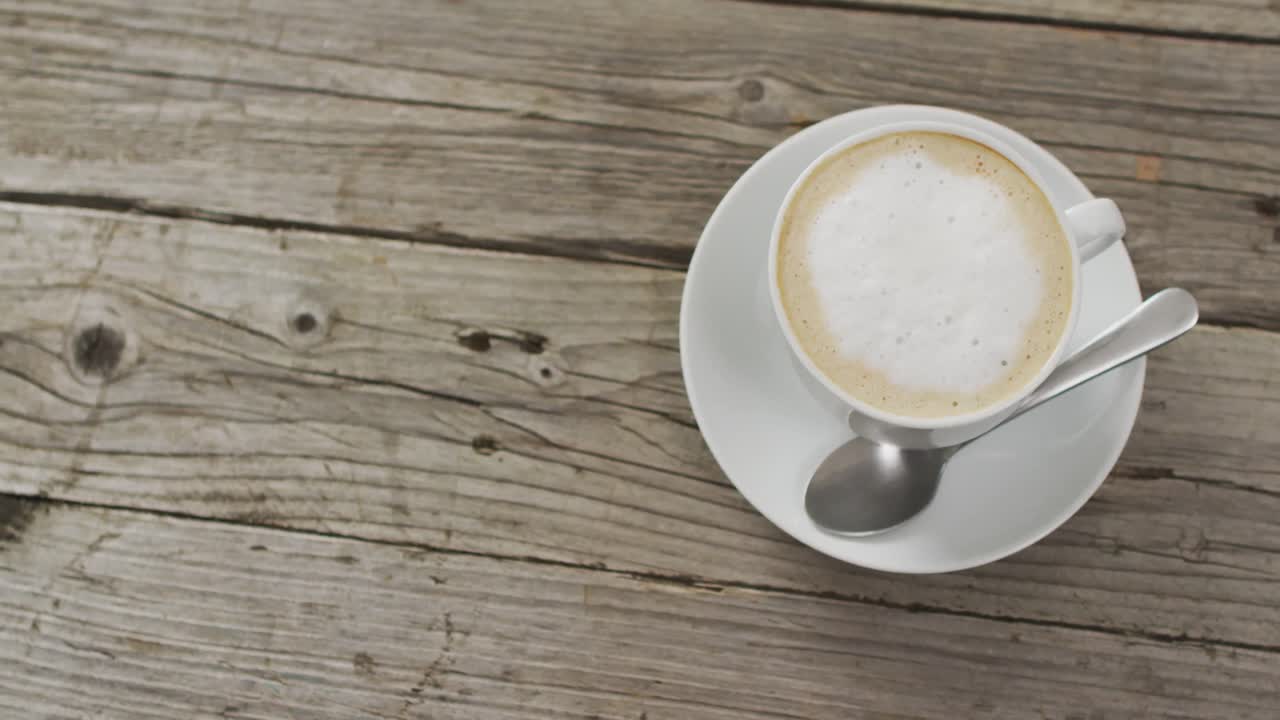 video de una taza blanca de café con leche sobre un fondo de madera