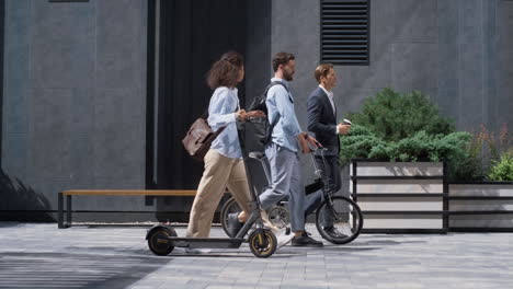 two colleagues going downtown street talking. shared eco-friendly transportation