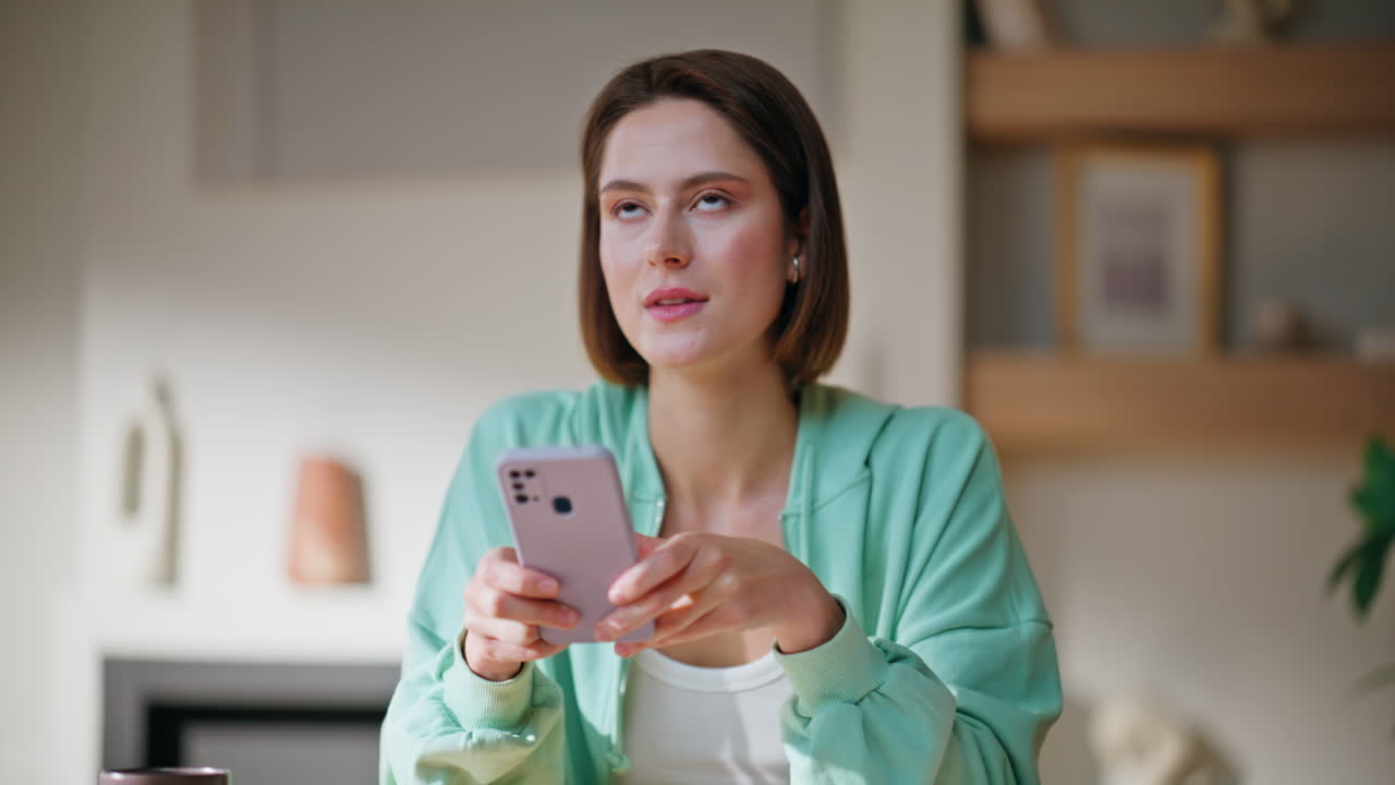 Lady typing cellphone sms sitting modern apartment living room smiling closeup
