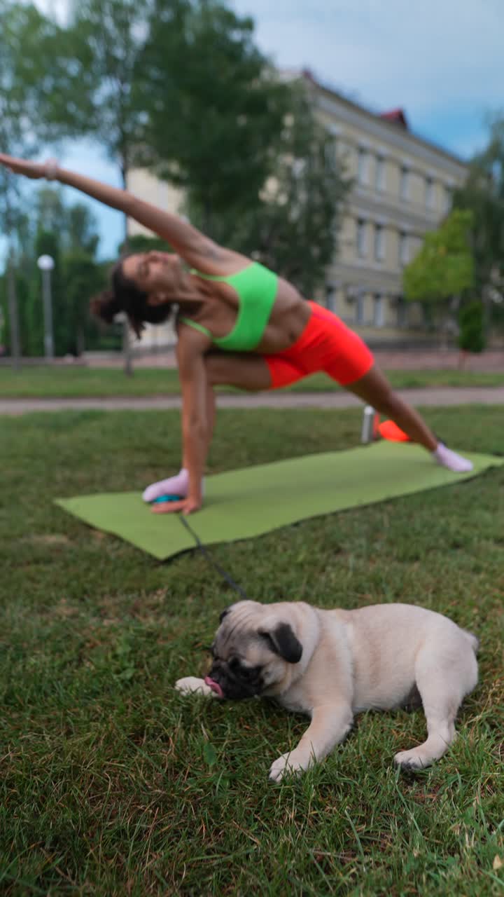 Woman doing yoga outdoors with a pug