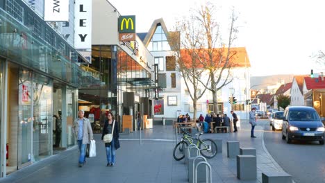 european city street scene with shops, restaurants, and people