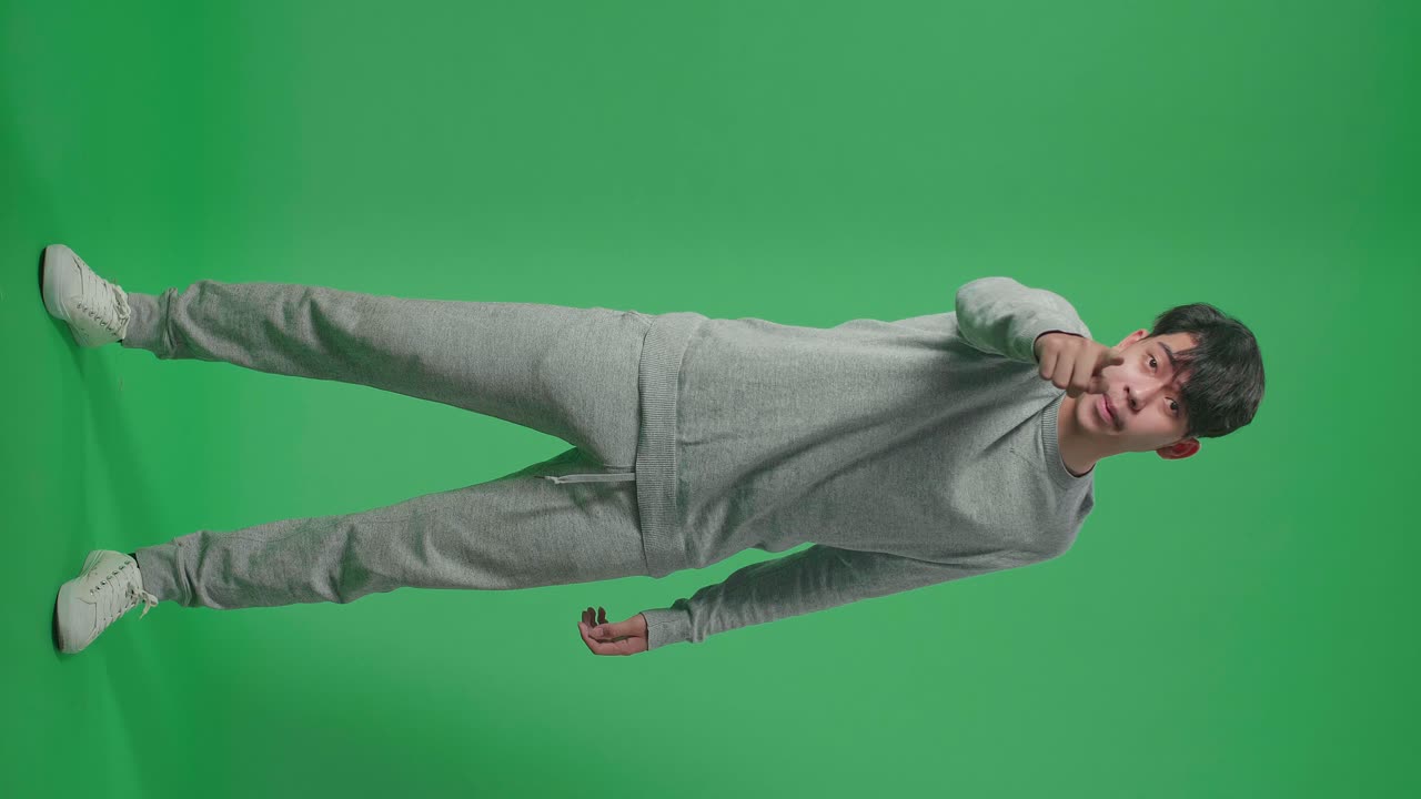 cuerpo lleno de hombre asiático enojado regañando mientras estaba de pie en la pantalla verde en el estudio