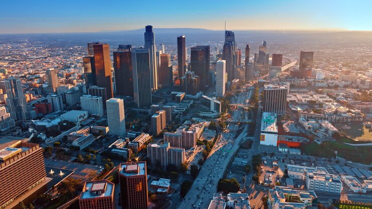 Los Angeles, USA, 11 gennaio 2026: Ampio panorama dello skyline di Los Angeles durante l'ora d'oro. Ampia vista aerea dell'espansione urbana, dei grattacieli e dell'autostrada con calda luce del tramonto e spazio per il testo.