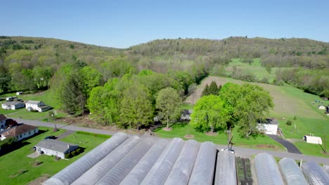 Soaring-Back-and-Past-a-Greenhouse-Unveiling-a-Row-of-Greenhouses-in-Spring-in-North-East-USA