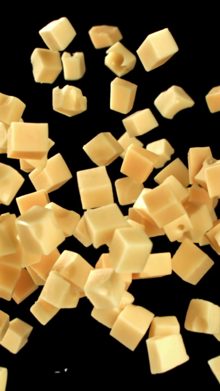 Cubes de fromage tombant au ralenti sur fond noir