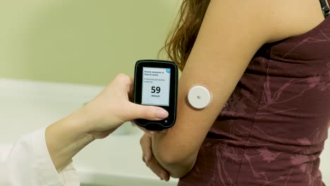 médico con una bomba de insulina conectada en el abdomen del paciente y sosteniendo la bomba de insulina en sus manos. concepto de diabetes.