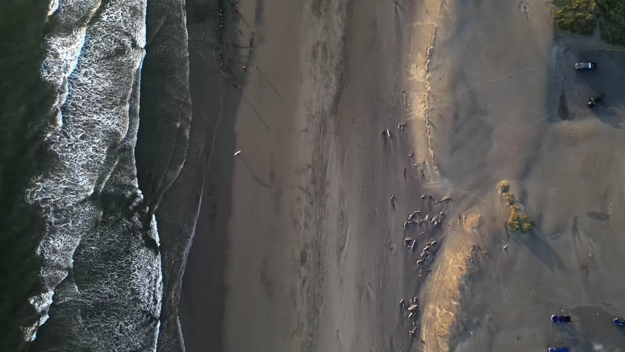 la playa de delaura en el parque estatal fort stevens, oregon, estados unidos en vista aérea hacia abajo, surfista de arriba hacia abajo caminando por la playa