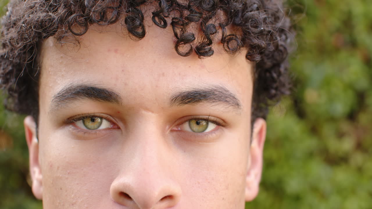 hombre biracial cara de cerca y mirando a la cámara al aire libre, cámara lenta