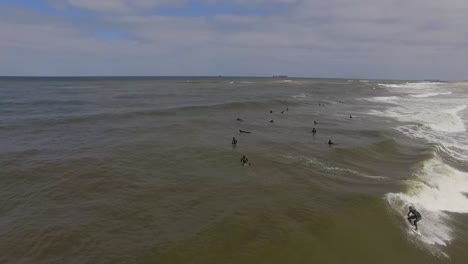 Aerial-view-of-surfers-on-their-surf-boards,-enjoying-vacation-on-the-beach