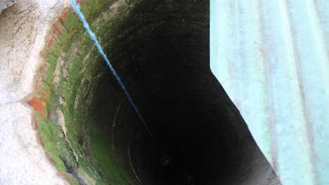 asian woman getting water from deep well - high-angle shot