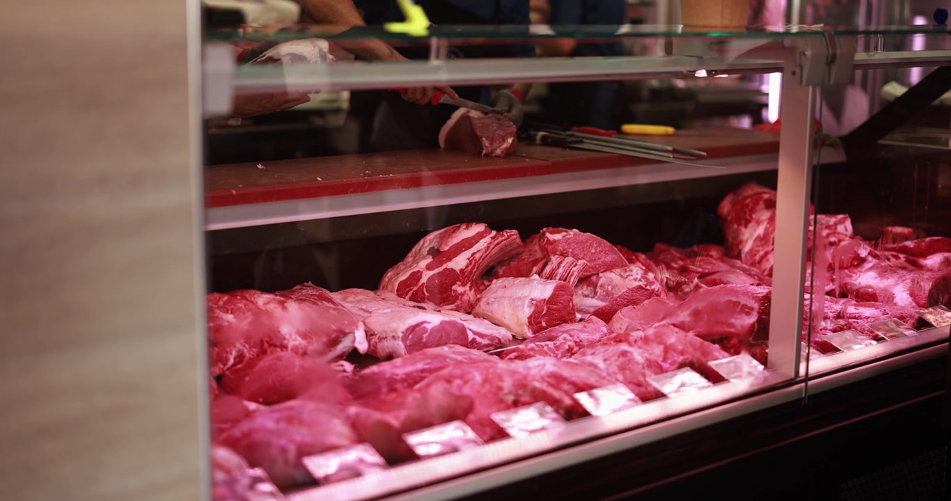 Butcher Preparing Cuts of Fresh Red Meat in a Shop