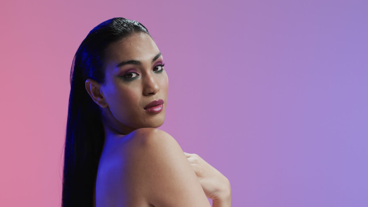 mujer biracial con cabello negro y maquillaje mirando a la cámara, copia espacio, cámara lenta