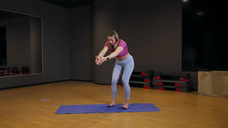 sporty woman stretching and exercising on the mat - wide shot