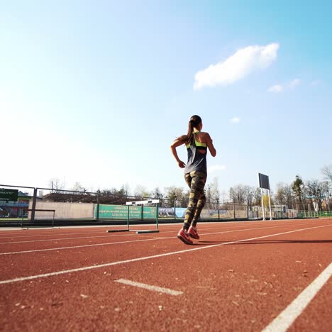 junge athletische frau, die auf der stadionstrecke läuft. schöner körper. gesunder fitness-lebensstil