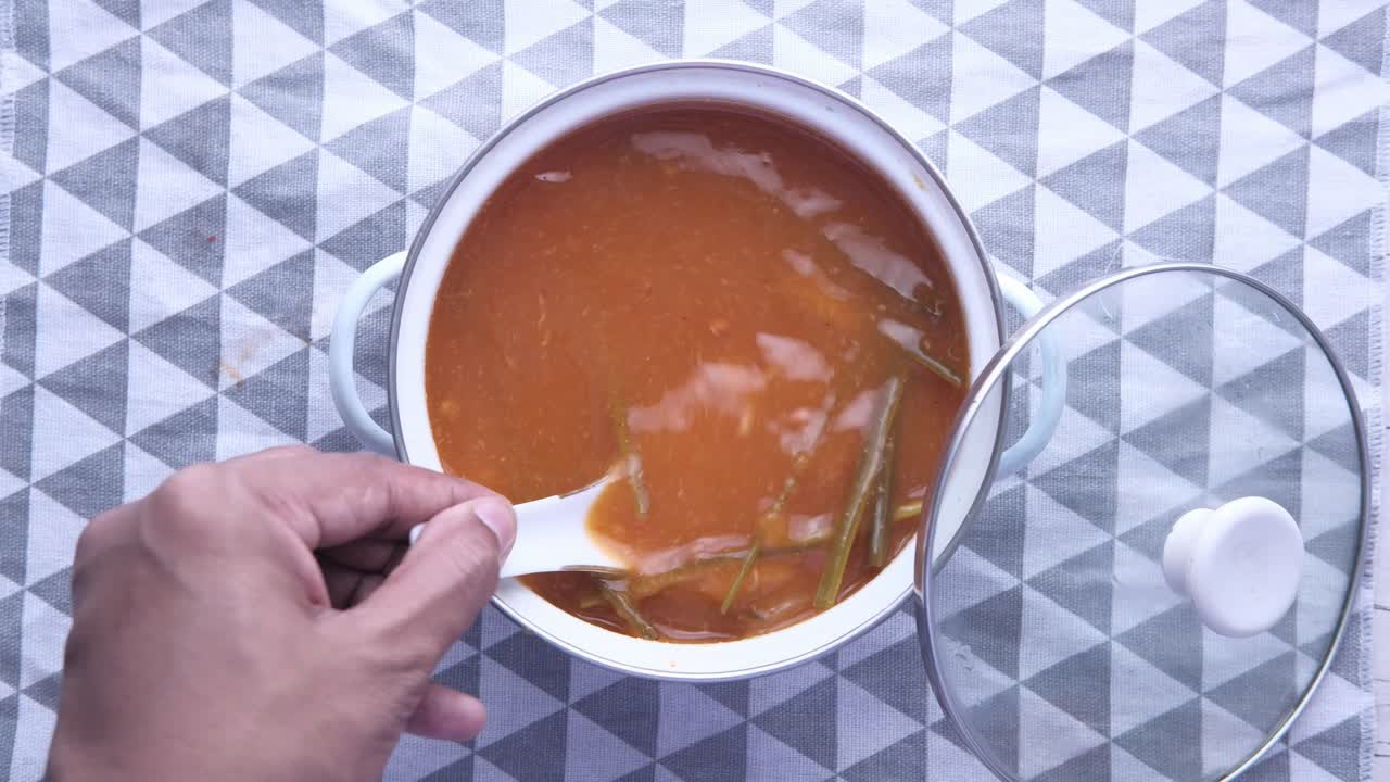 Person holding spoon over a bowl of soup