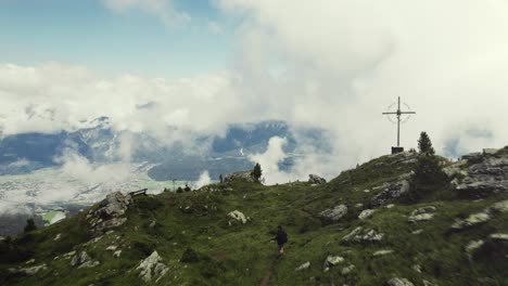 aerial drone shot of a grass covered mountain top with a person hiking along a small trail
