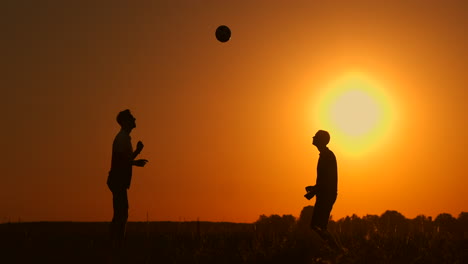 dos niños jugando al fútbol al atardecer. silueta de niños jugando con una pelota al atardezer. el concepto de una familia feliz.