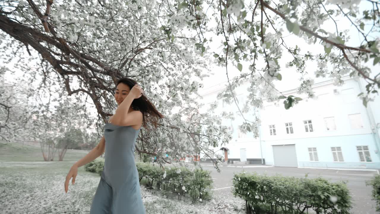 Woman in a Blue Dress under Blooming Tree