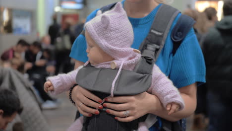 cute baby girl in a baby carrier at airport