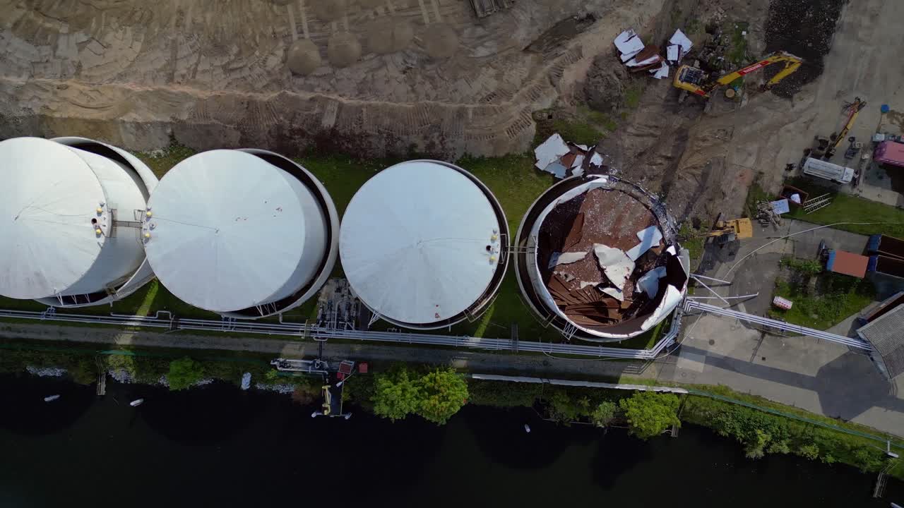 bird's eye view drone of a Demolition Decommissioning Industrial storage tanks holding oil and gas products next to a busy construction area. Great aerial view flight overflight flyover drone