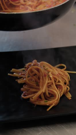 chef grabbing spaghetti with lobster from the pan and plating the gourmet dish
