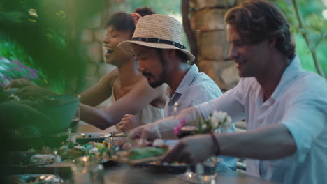 summer dinner party with friends eating mediterranean food sitting at table outdoors chatting enjoying feast 4k footage