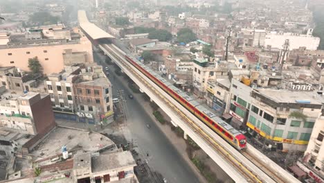 Luftaufnahme-Des-U-Bahn-Zugs-Der-Orangefarbenen-Linie,-Der-In-Der-Nähe-Der-Mcleod-Road-In-Lahore-Auf-Einer-Erhöhten-Strecke-Abfährt