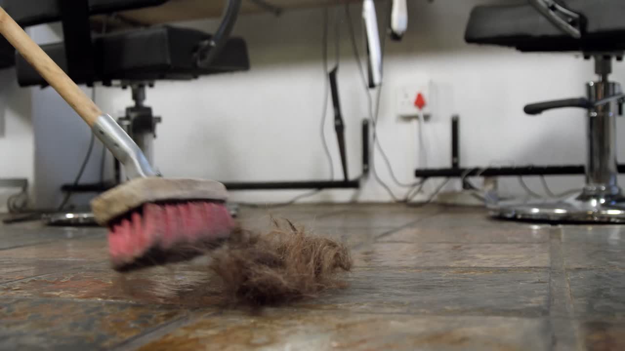 peluquero limpiando los residuos en el suelo