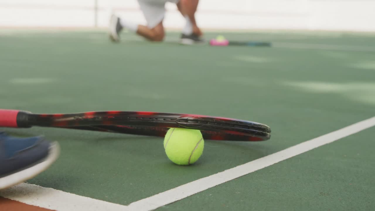 Noen som plukker opp tennisracket og ball