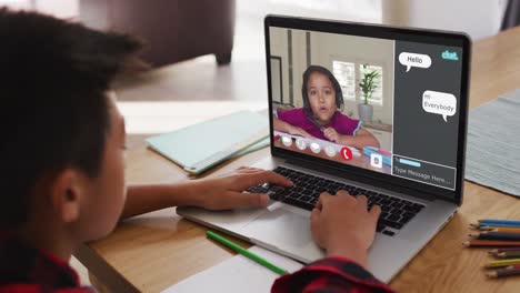 Schoolboy-using-laptop-for-online-lesson-at-home,-with-girl-talking-and-web-chat-on-screen