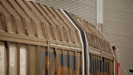 Side-view-of-a-driving-rusty-train-carriage,-focusing-on-the-roof-structure