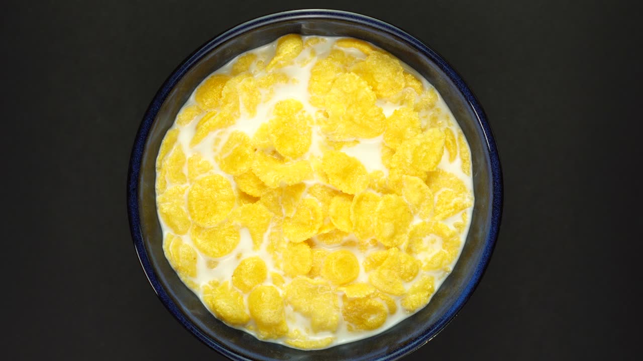 Rotazione di corn flakes con latte isolati su sfondo nero. Rotazione a 360 gradi. Concetto di colazione sana.