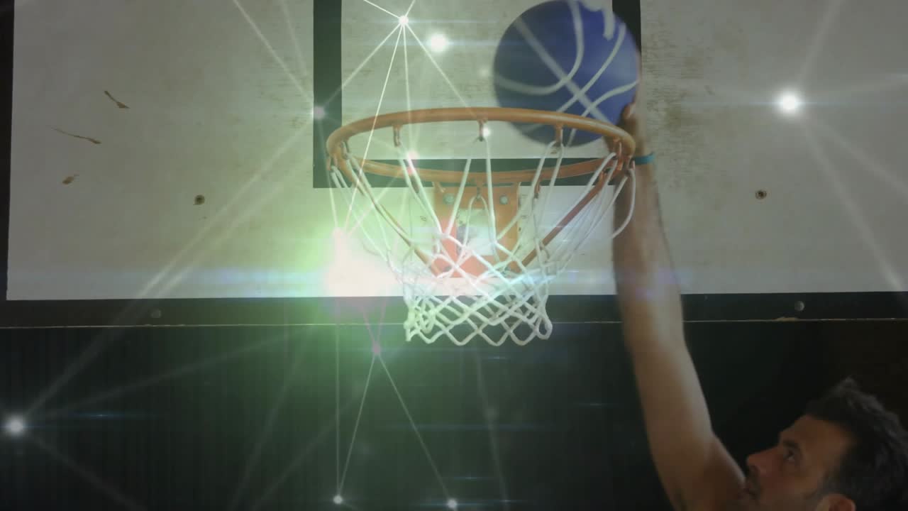 Male player with ball entering, pushing ball through hoop to score, sports overlay tracing ball