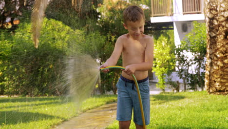 Niño-Regando-El-Césped-Con-Manguera