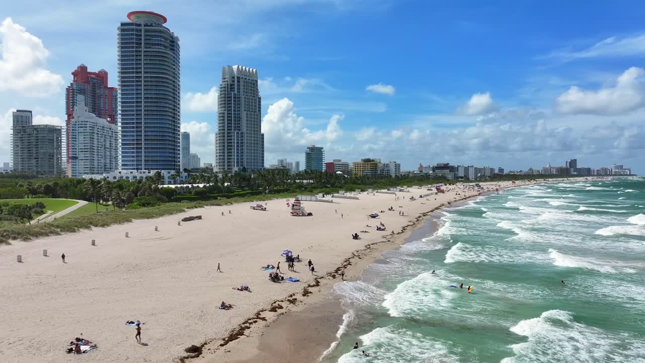 백그라운드에서 시내 스카이라인과 함께 마이애미 해변을 즐기는 사람들